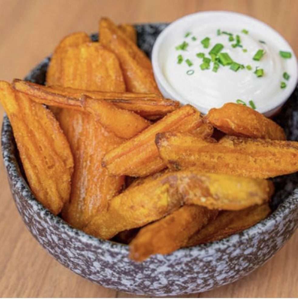 Bowl of golden sweet potato wedges with a chive dip
